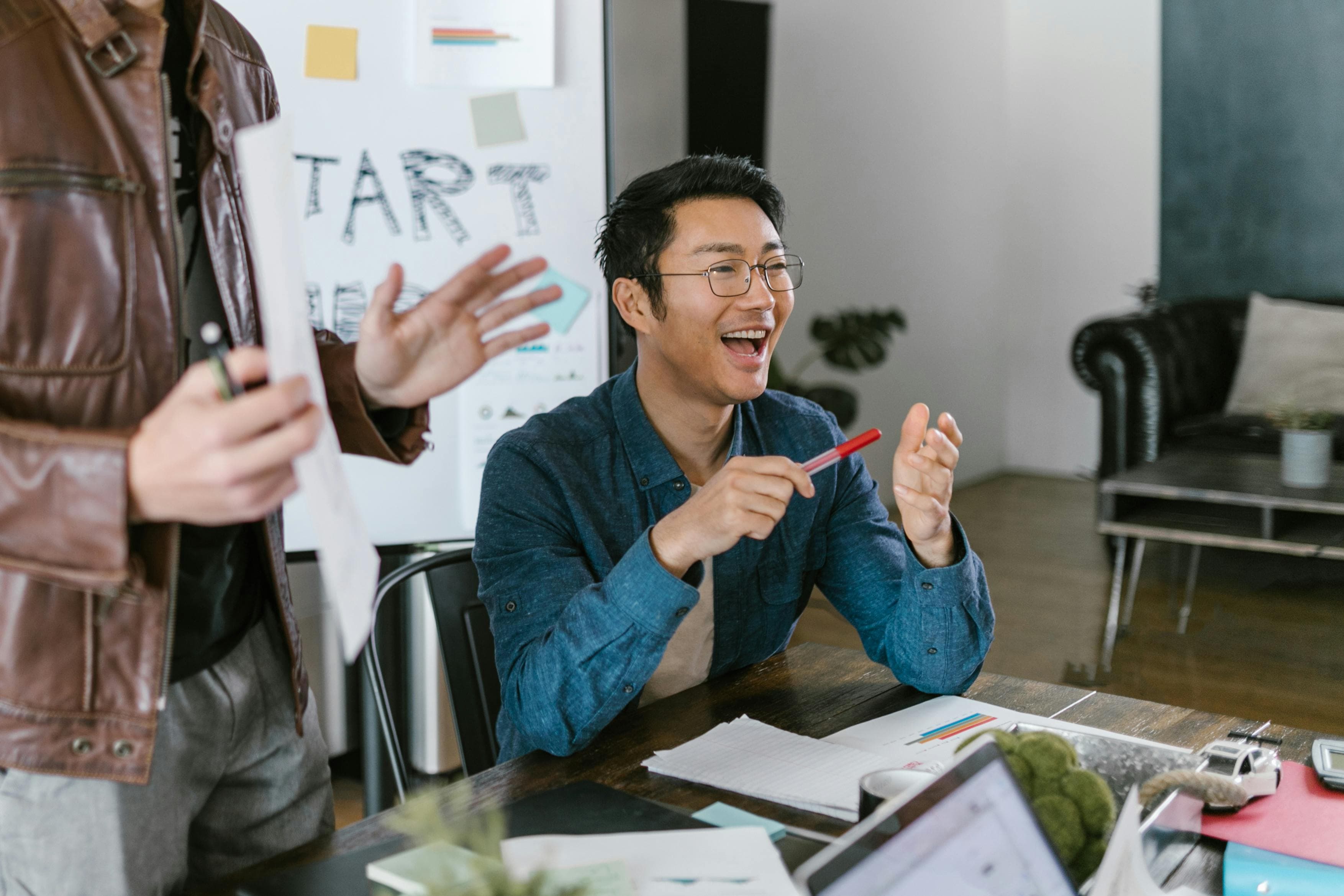 An asian man stressed over his work in his office.